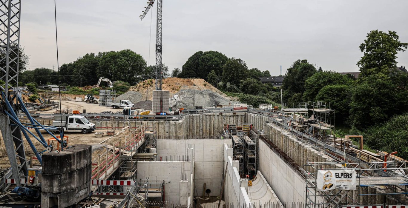Bauplatz mit schwerem Gerät, Erdarbeiten und einer offenen Baugrube.