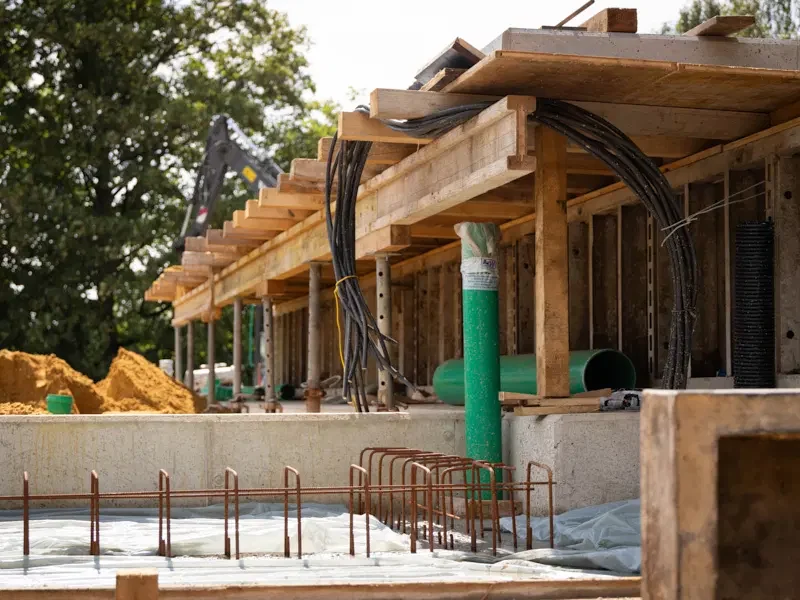 Bauplatz mit Holzgerüst, Rohren und Baumaterialien für ein Gebäude.