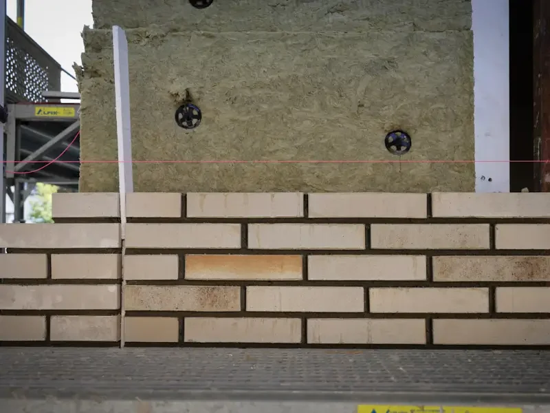 Mauerwerk aus hellen Ziegeln mit einer unbeschnittenen Steinreihe.