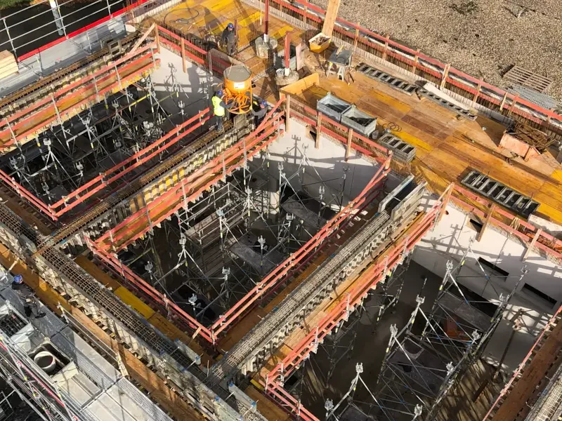 Blick auf Baustelle mit Betonschächten und Baugeräten in verschiedenen Phasen der Konstruktion.