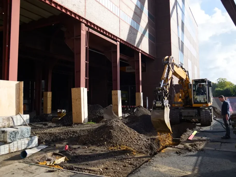 Bauarbeiter mit Bagger, der Erde an einem Baustellenstandort bewegt.