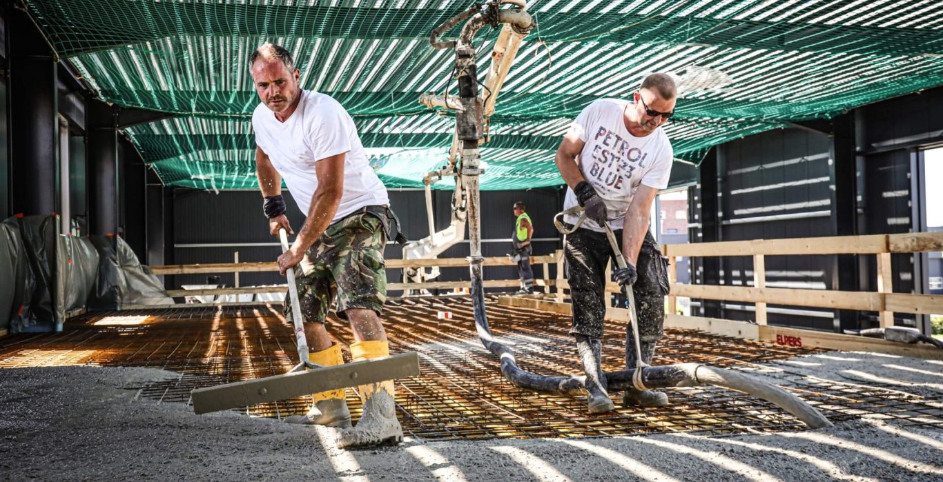 Bauarbeiter gießen Beton auf einer Baustelle.