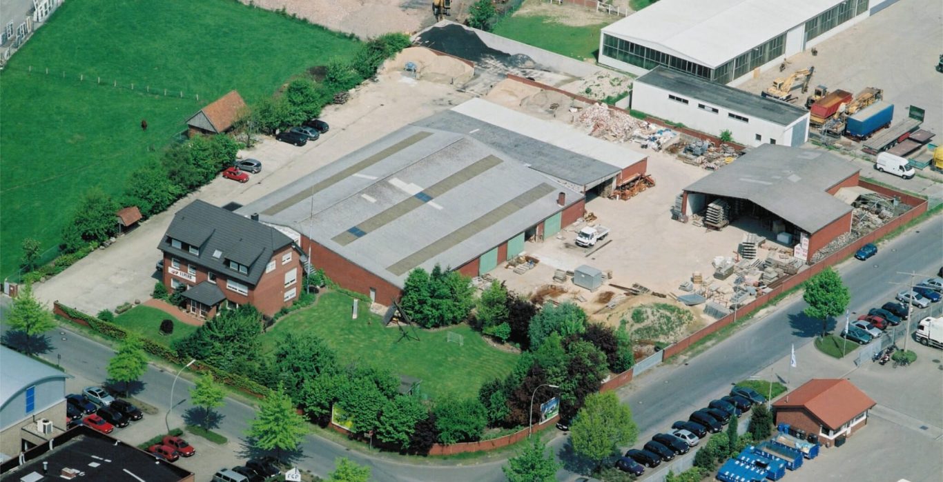 Luftaufnahme eines Firmengeländes mit mehreren Gebäuden und Parkplätzen.