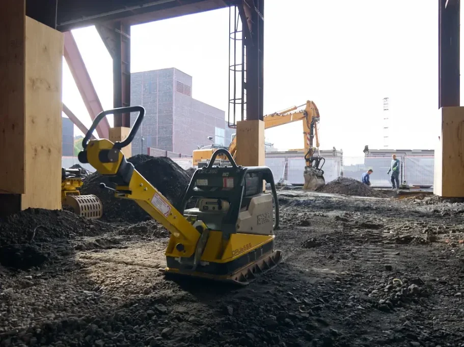Baustelle mit Geräten und Arbeitern, die an einem Fundament arbeiten.