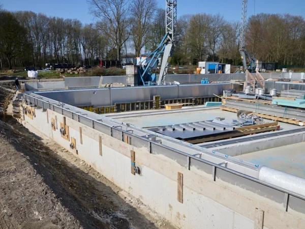 Bau eines Fundaments mit Baustellenmaschinen und Material in einer ländlichen Umgebung.