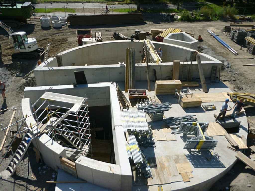 Bauplatz mit mehreren Baugeräten und unvollendeten Betonstrukturen.