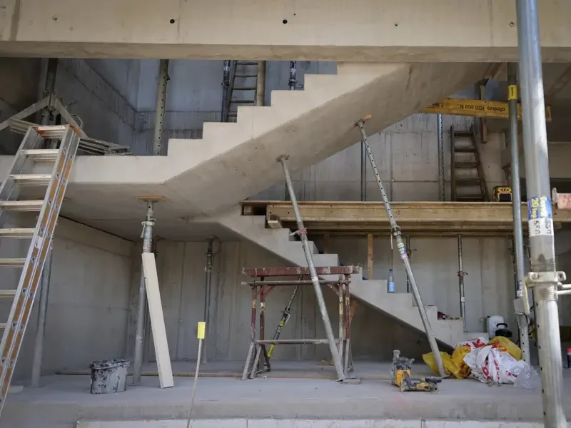 Baustelle mit Treppe aus Beton und Baugeräten, unvollendete Struktur.